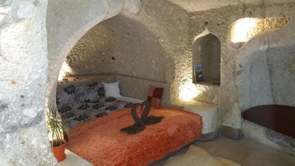 - une chambre avec un lit dans une pièce en pierre dans l'établissement Riolit Barlangszállás Szomolya, à Szomolya