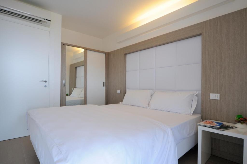 a bedroom with a white bed and a large window at Aparthotel Tiziano in Grado