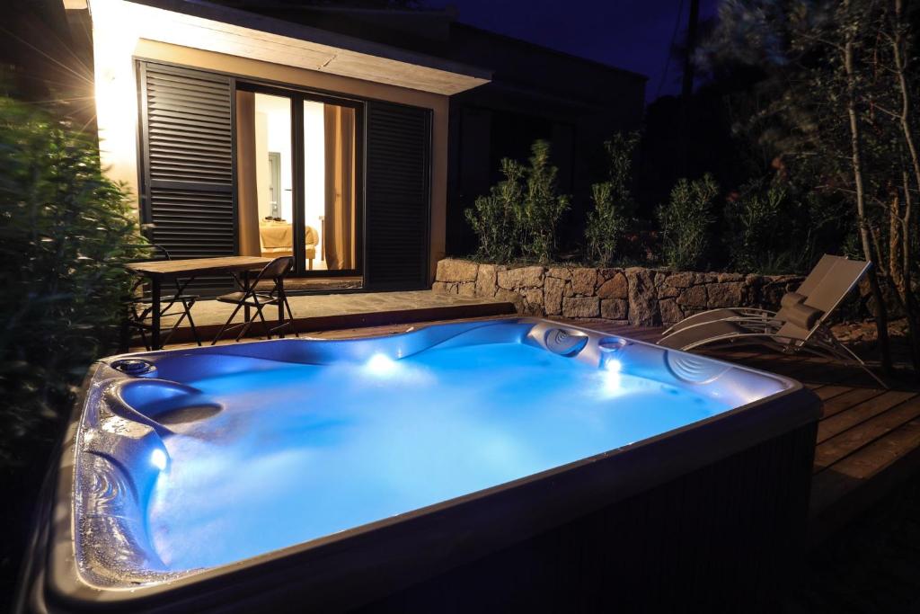 a blue hot tub in a backyard at night at Hôtel confidentiel Le Grecale in Pianottoli-Caldarello