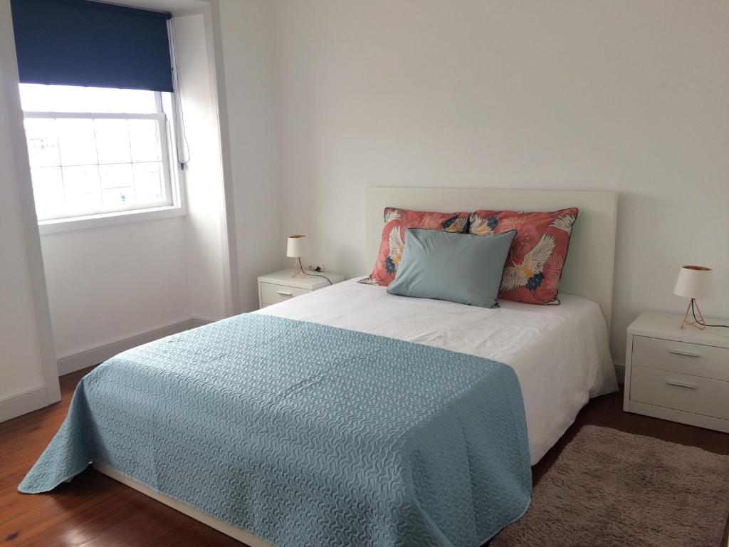 um quarto com uma cama com um cobertor azul e uma janela em Retiro dos Reis em Horta