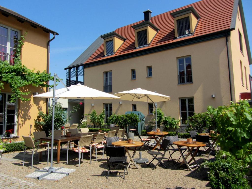 un patio con mesas y sombrillas frente a un edificio en Hotel Weinblatt, en Sommerach