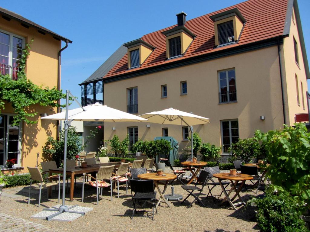 a patio with tables and umbrellas in front of a building at Hotel Weinblatt in Sommerach