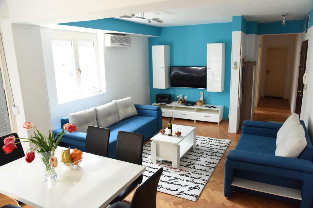 a living room with a blue couch and a table at Kiara Apartments Skopje in Skopje