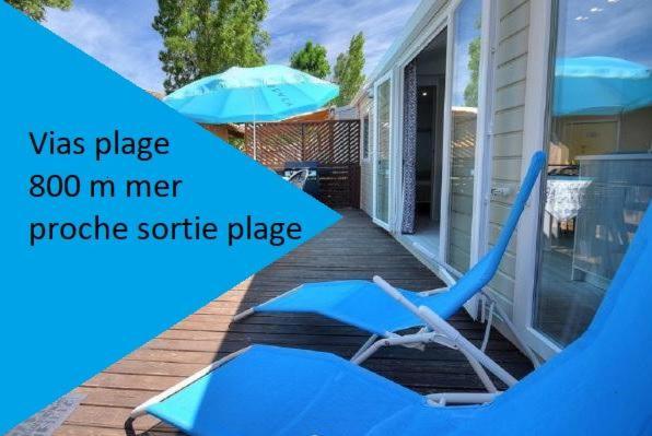 una silla azul sentada en un porche con sombrilla en mobilhome 500m mer camping LA CARABASSE, en Vias