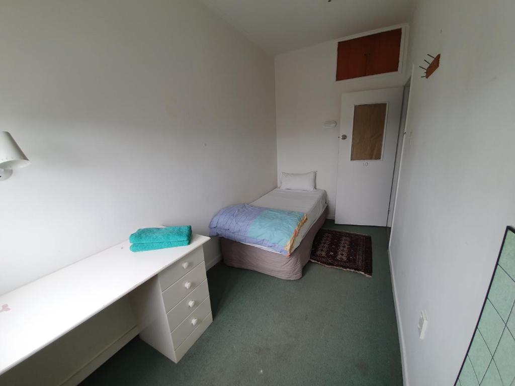 a small bedroom with a bed and a desk at Uenuku Lodge in Auckland