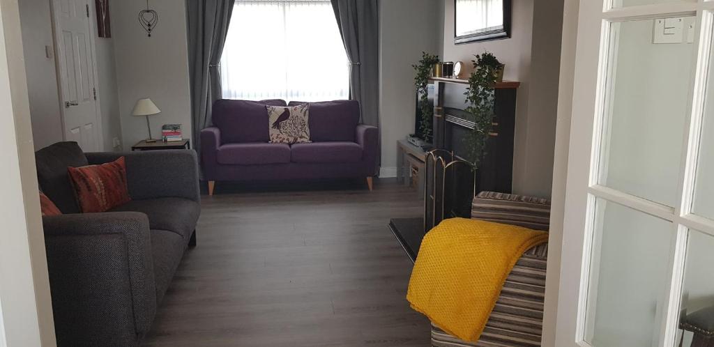 a living room with a purple couch and a window at The Abbey in Ballycastle