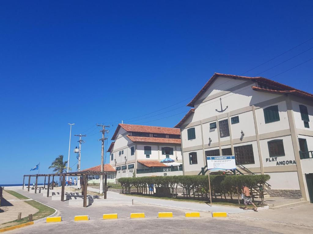 een gebouw aan de kant van een strand met een persoon die er langs loopt bij Flat Âncora in Cabo Frio