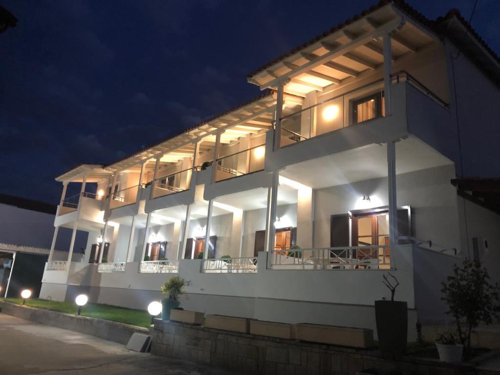 Un grand bâtiment blanc avec balcon est disponible la nuit. dans l'établissement Filoxenia Studios, à Afytos