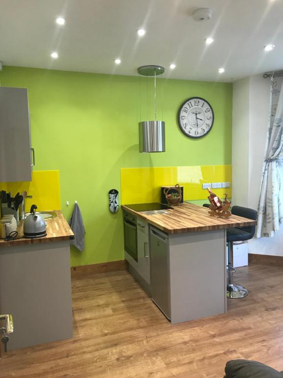 a kitchen with a clock on a green wall at Nant Apartment - Ground Floor in Menai Bridge
