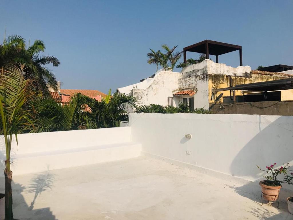 a white house with a white wall and palm trees at Calle de la iglesia 35-59 in Cartagena de Indias