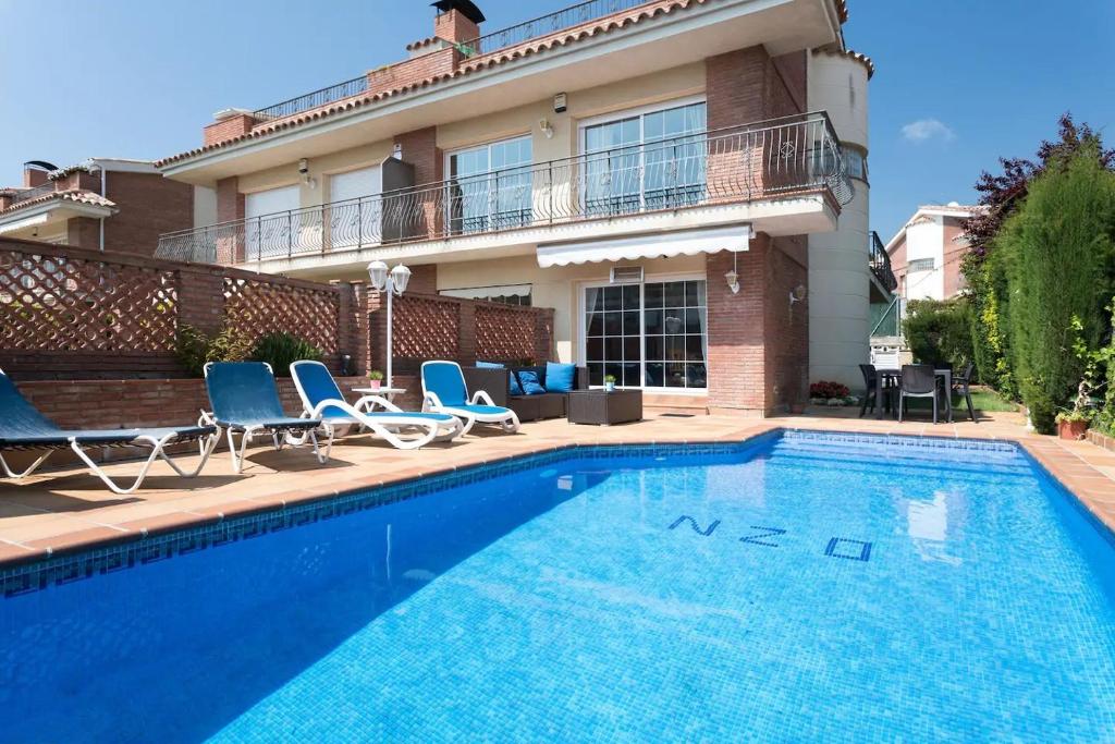 a swimming pool with chairs and a house at Casa Tomas in Sant Vicenç de Montalt