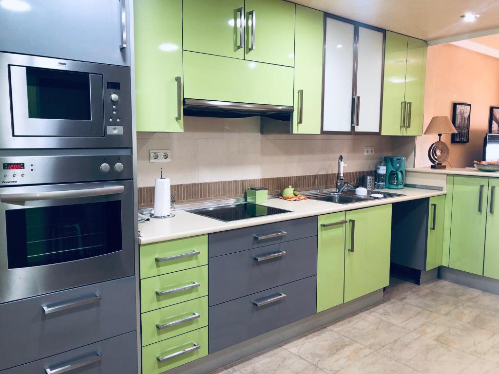 a kitchen with green cabinets and stainless steel appliances at Piso lujoso in Puerto de Mazarrón