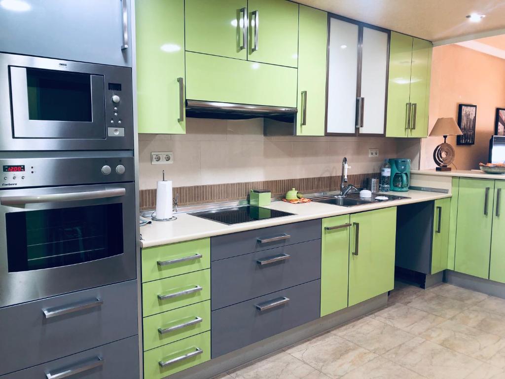 una cocina con armarios verdes y electrodomésticos de acero inoxidable en Piso lujoso, en Puerto de Mazarrón