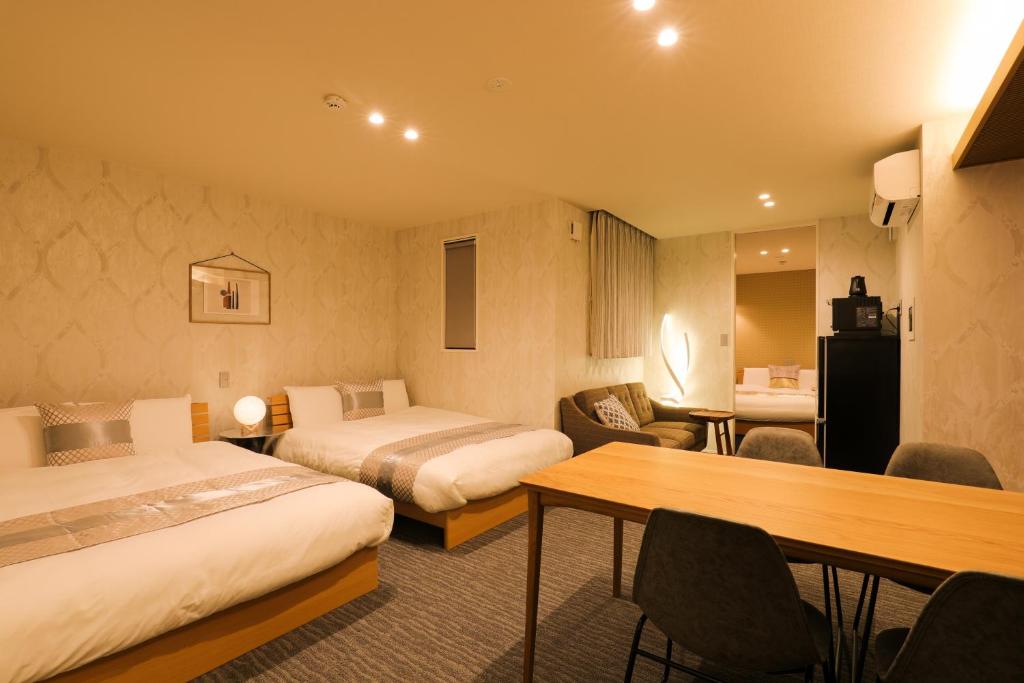 a hotel room with two beds and a table and chairs at GRAND BASE Gion in Fukuoka