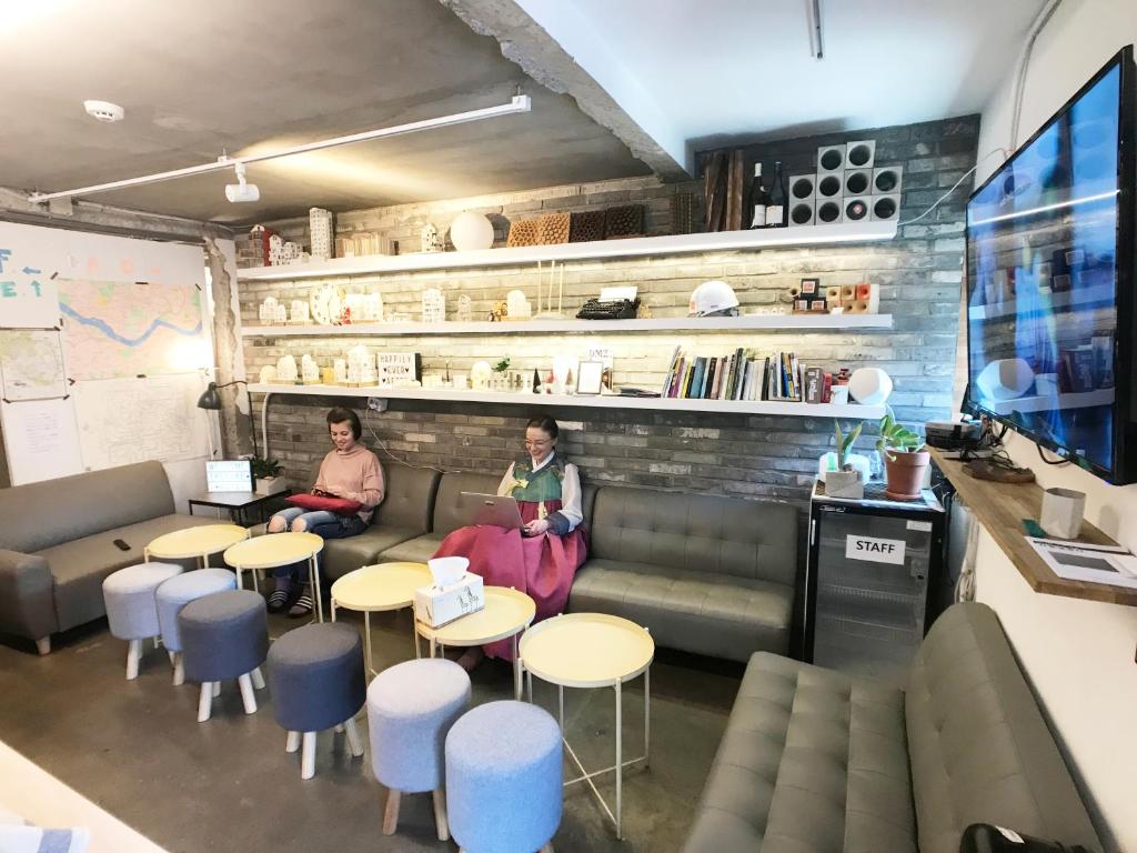 two people sitting in a room with tables and chairs at The Cube Hotel in Seoul