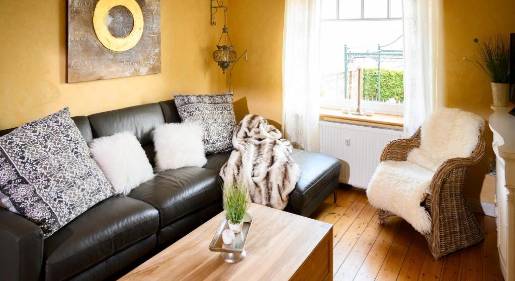 a living room with a black leather couch and a table at Altes Zollhaus Casa Sandstrand in Scharbeutz