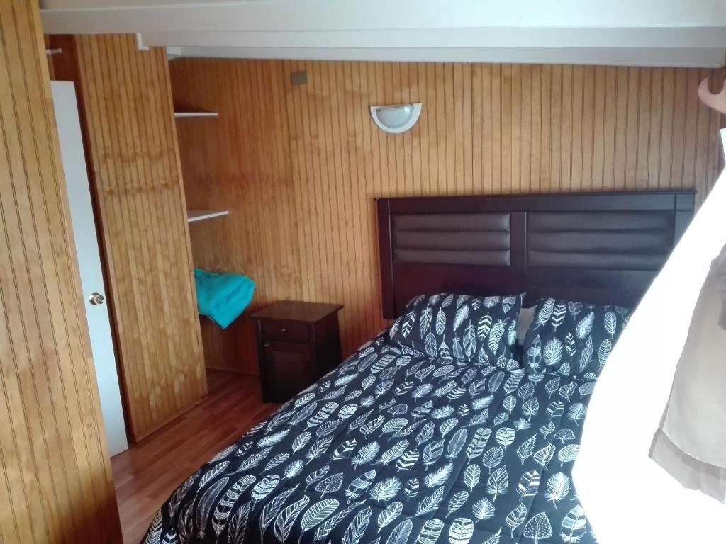 1 dormitorio con 1 cama y suelo de madera en Tres de junio, en Puerto Montt