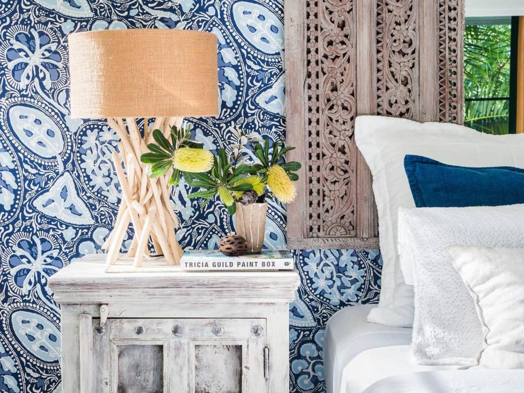 a bedroom with blue and white wallpaper and a table with a lamp at Villa Aitutaki in Byron Bay