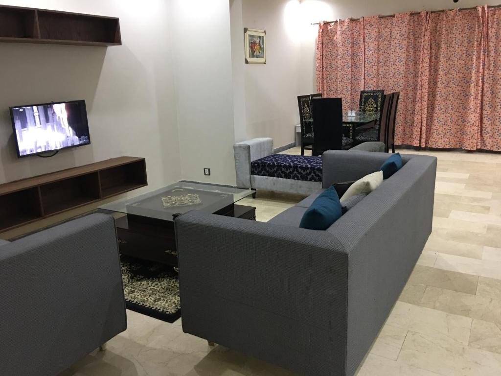 a living room with a couch and a tv at Apartment near Shaukat Khanum in Lahore