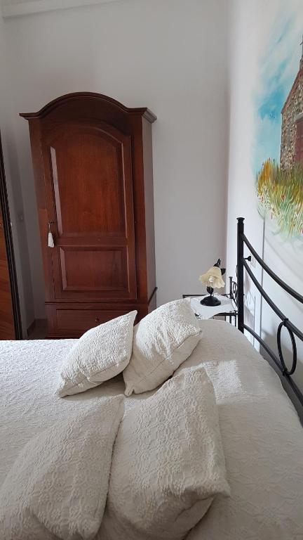 una camera da letto con un letto con lenzuola bianche e una testiera in legno di Su Cunventu a Muravera