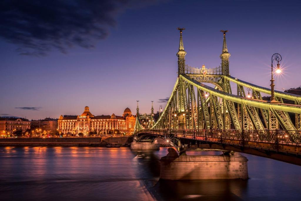 a bridge over a body of water with a city at Danubius Hotel Gellért in Budapest