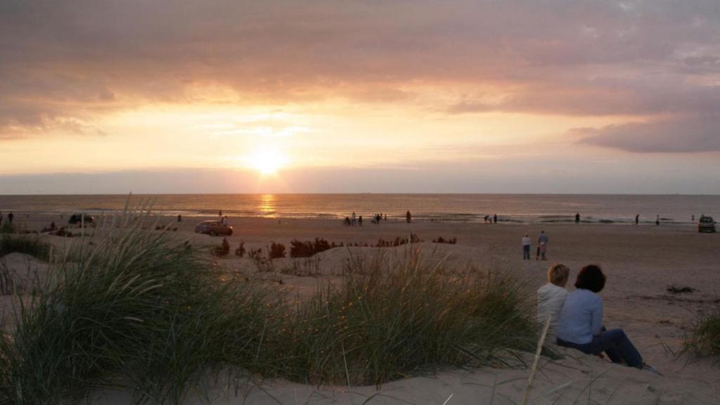 dos personas sentadas en la playa viendo la puesta de sol en Tversted Strandpark, en Bindslev