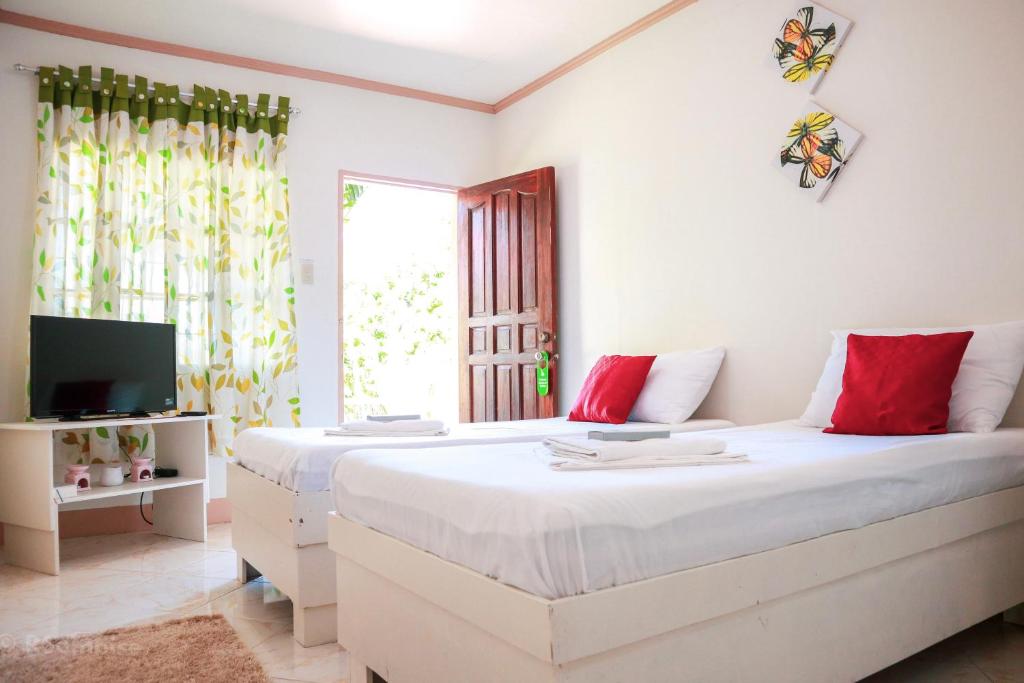 a bedroom with a large white bed with red pillows at RQS Hostel in Tacloban