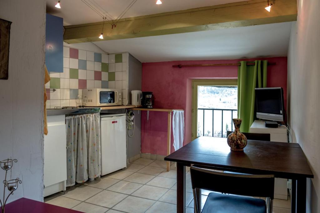 a kitchen with a table and a television in it at Gîte Chambres d&#39;hôtes Le Bellevue in Montbrun-les-Bains