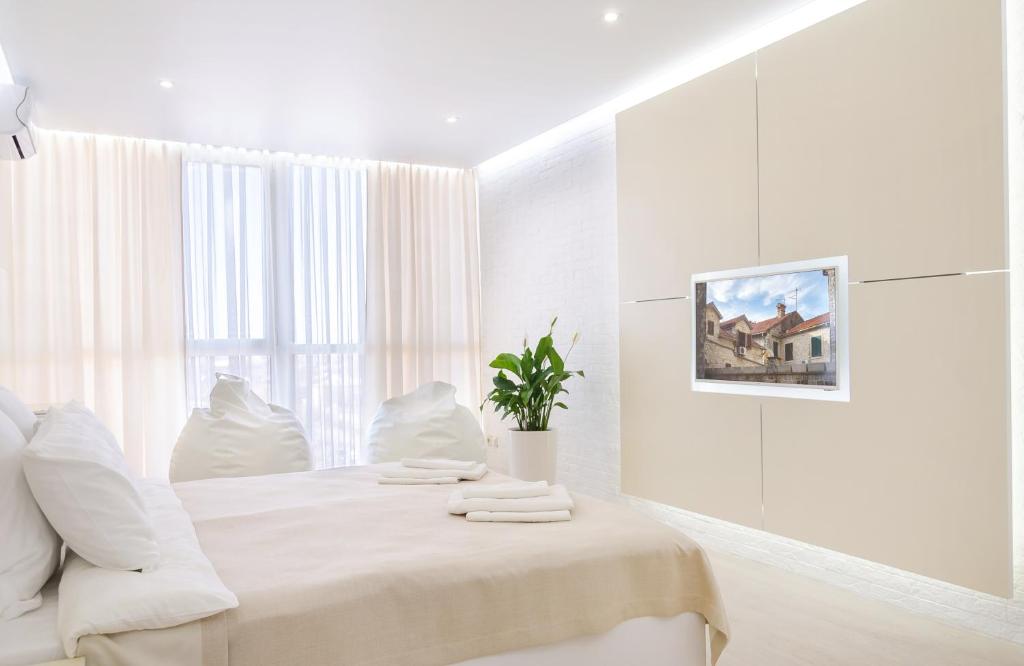 biała sypialnia z łóżkiem i oknem w obiekcie The First Apart Hotel w mieście Tomsk