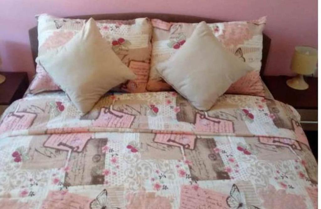 a bed with pink and white sheets and pillows at Apartment Jovana Vrnjačka Banja in Vrnjačka Banja
