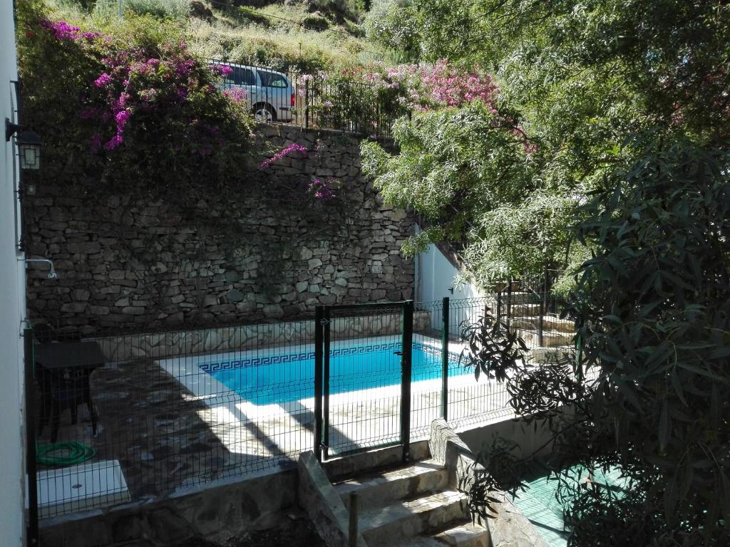 a swimming pool next to a stone wall at Casa MamaTere in Benamahoma