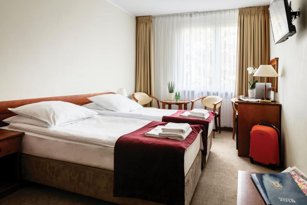 a hotel room with two beds and a desk at Hotel Zawisza in Bydgoszcz