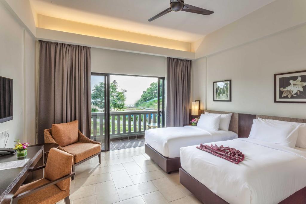 a hotel room with two beds and a balcony at Camar Resort Langkawi in Pantai Cenang