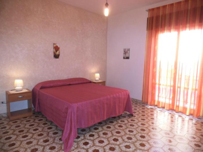 una camera con un letto con copriletto rosso di Le spezie 2PD a Castellammare del Golfo