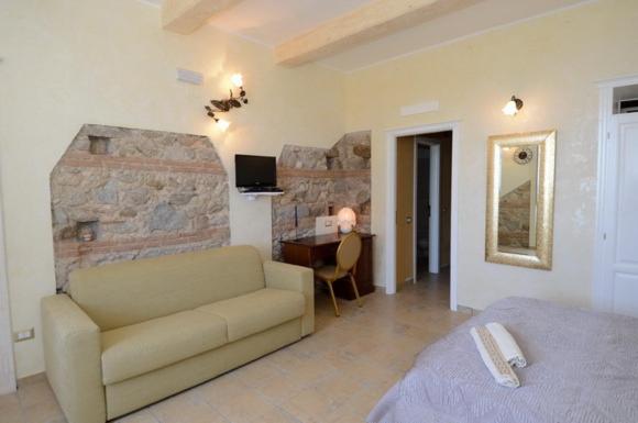 a living room with a couch and a stone wall at Residenza Casale San Francesco in Tropea