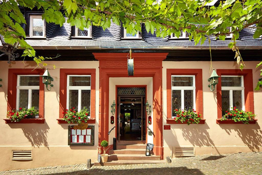 ein Gebäude mit roten Zierleisten und Blumen in den Fenstern in der Unterkunft Hotel Doctor Weinstube in Bernkastel-Kues