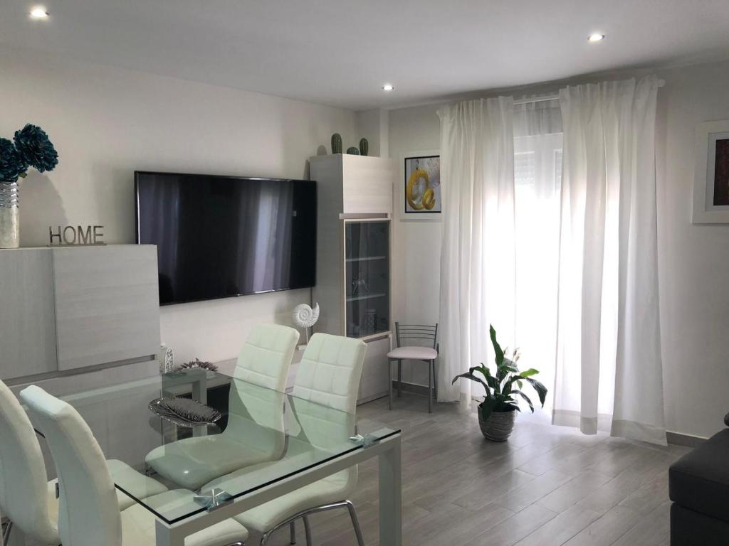 een woonkamer met een televisie en een tafel en stoelen bij APARTAMENTO 128 ESPINEL in Ronda
