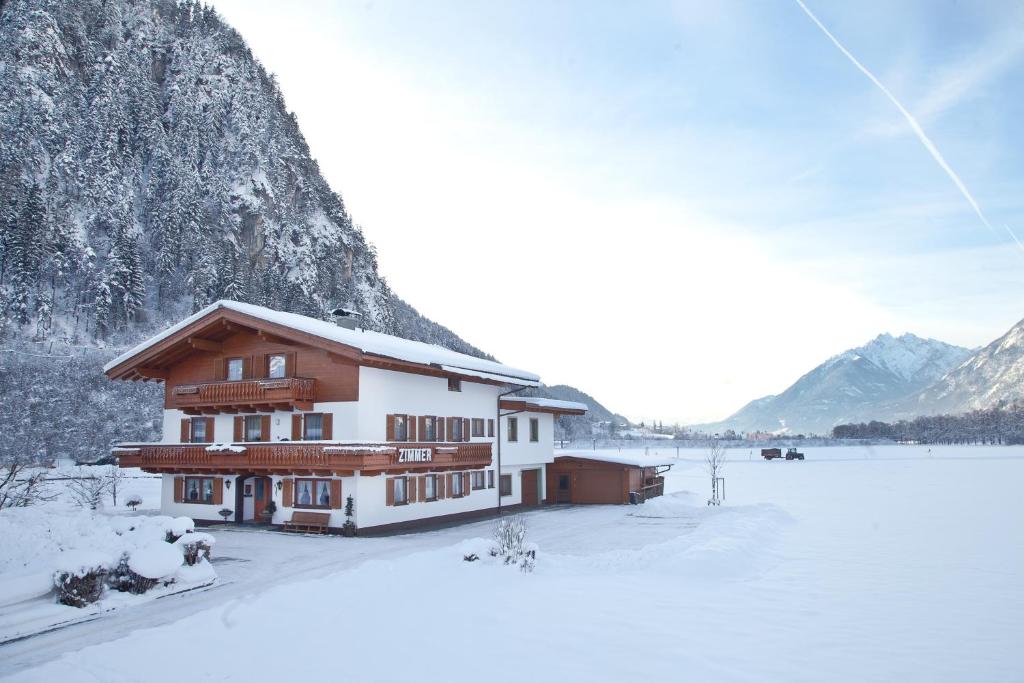 a building in the snow next to a mountain at Gästehaus Luxner in Strass im Zillertal