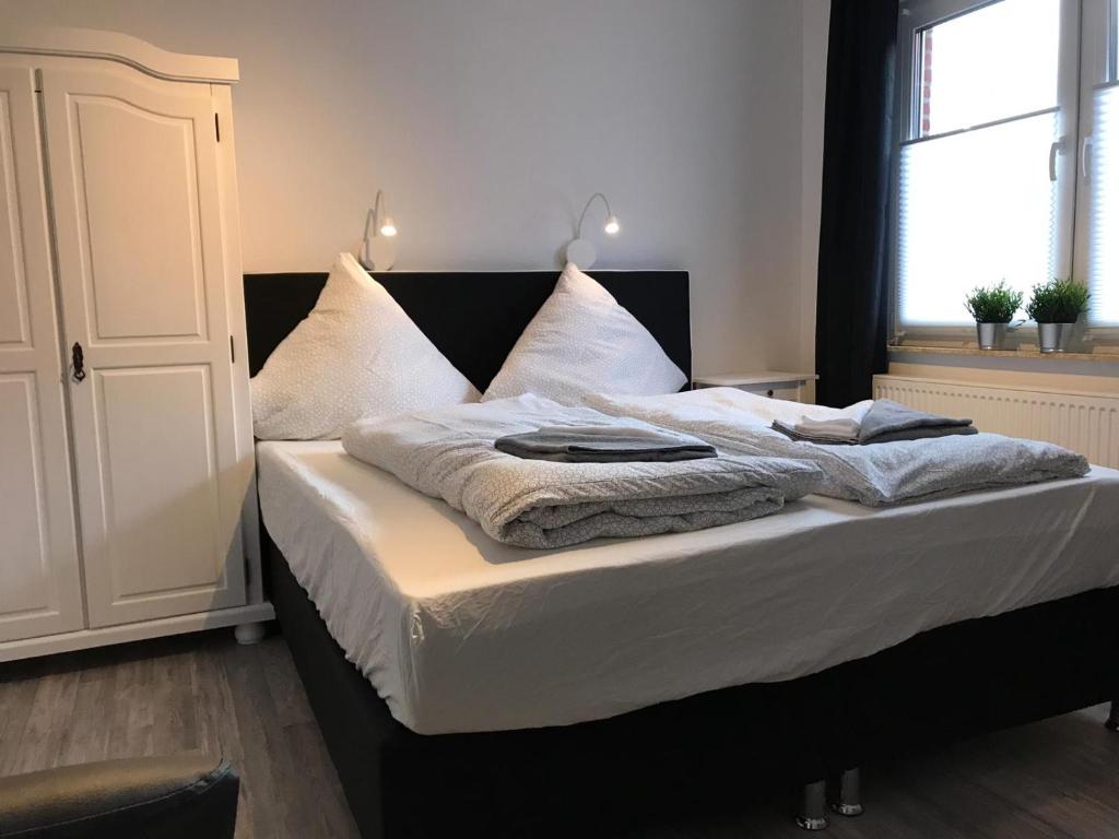 a bedroom with a bed with white sheets and pillows at Kleine Möwe in Neßmersiel