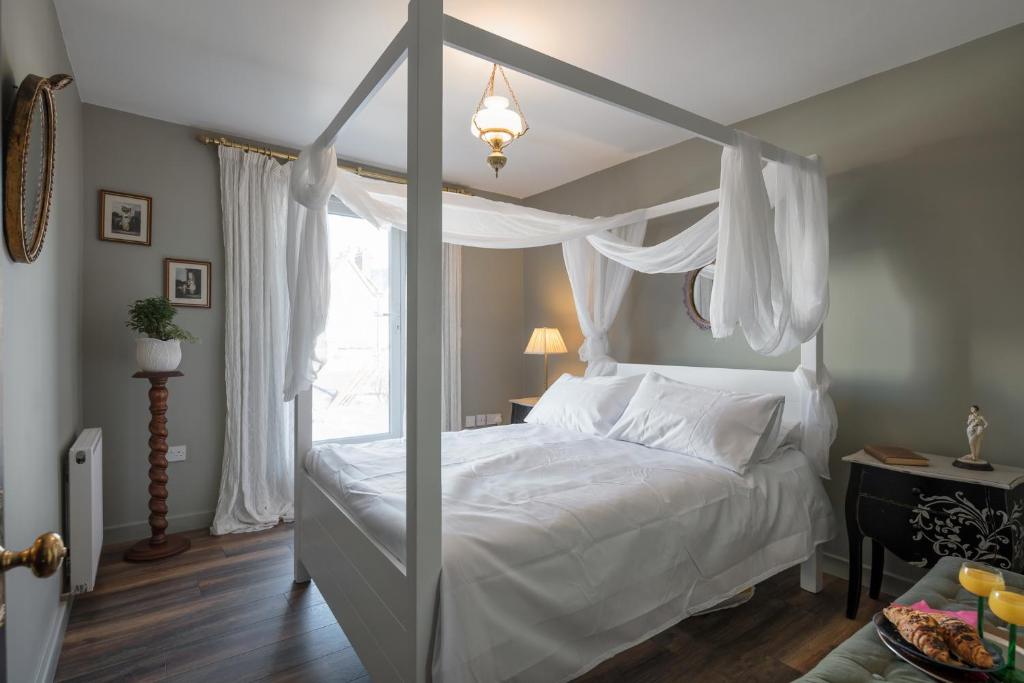 sypialnia z białym łóżkiem z baldachimem i oknem w obiekcie Courcy Road - 7 bedroom - sleeps up to 22 w Londynie