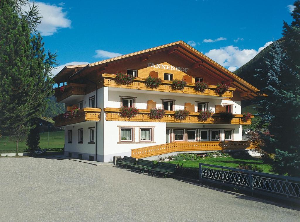 ein großes weißes Gebäude mit Blumen auf dem Balkon in der Unterkunft Pension Tannenhof in St. Johann im Ahrntal