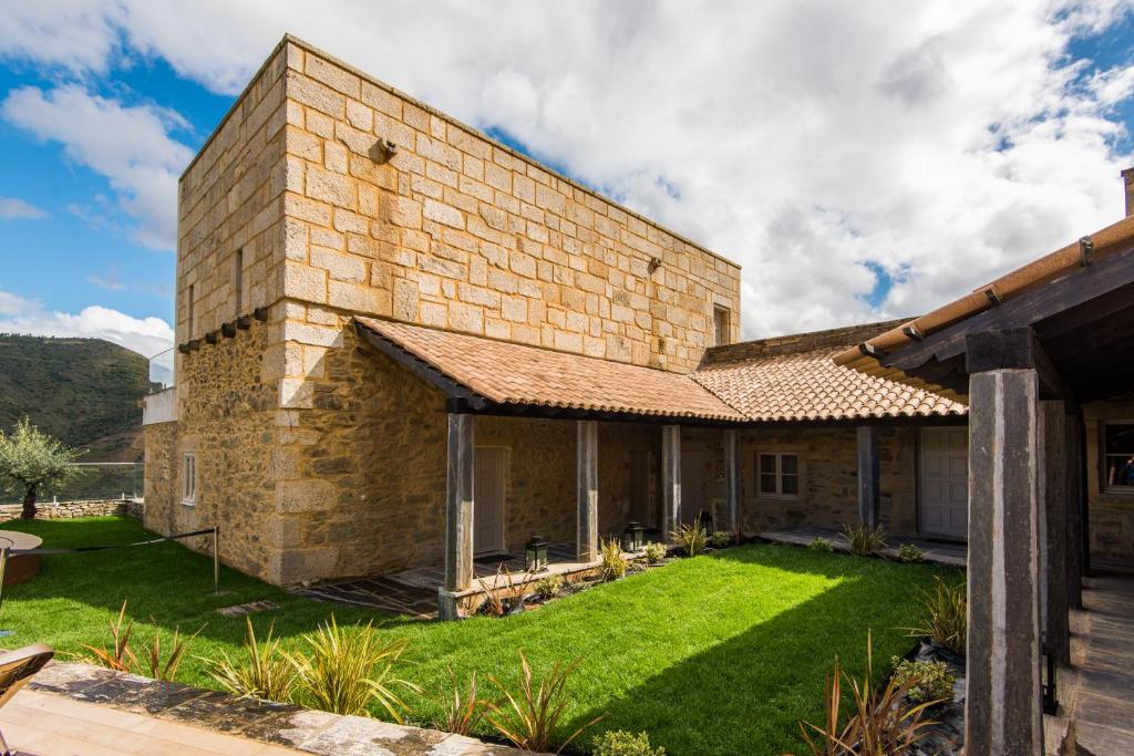 an old brick building with a grass yard at Vila Gale Douro Vineyards in Armamar