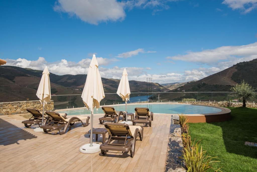 a patio with chairs and umbrellas next to a pool at Vila Gale Douro Vineyards in Armamar
