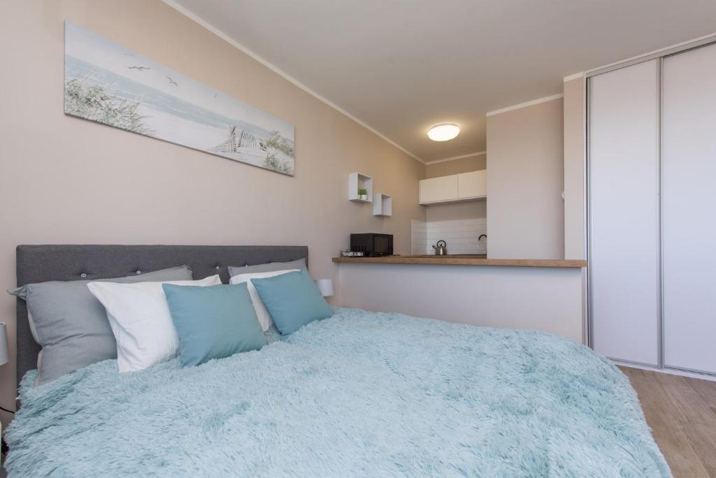 - une chambre avec un grand lit et des oreillers bleus dans l'établissement Avis Apartments - Gdynia Skwer Kościuszki, à Gdynia