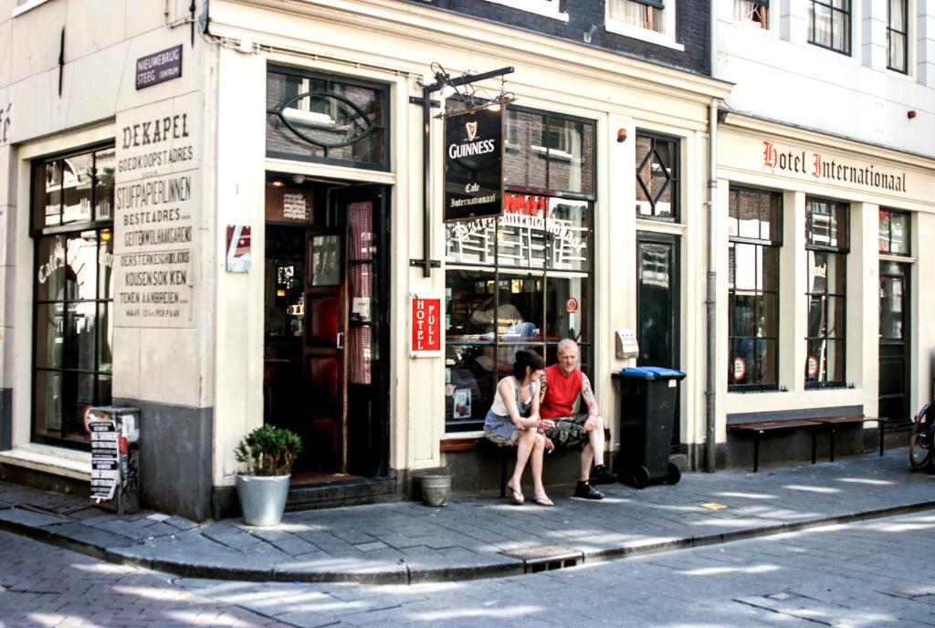 Deux femmes assises à la fenêtre d'un magasin dans l'établissement Hotel Internationaal, à Amsterdam