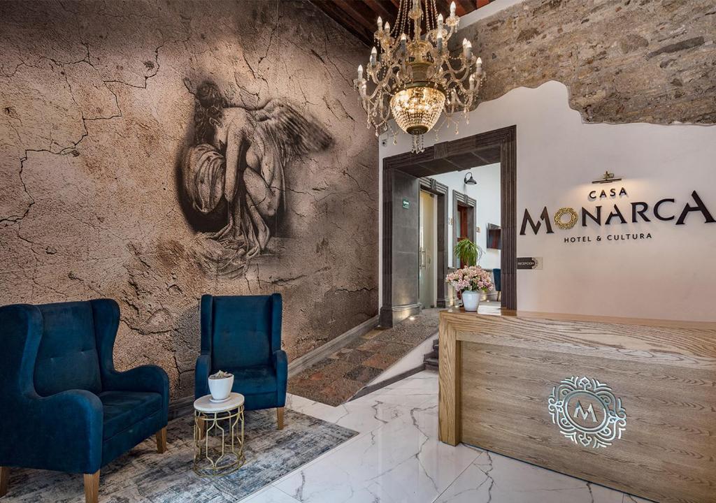 a lobby with two blue chairs and a mirror at Hotel Casa Monarca in Puebla