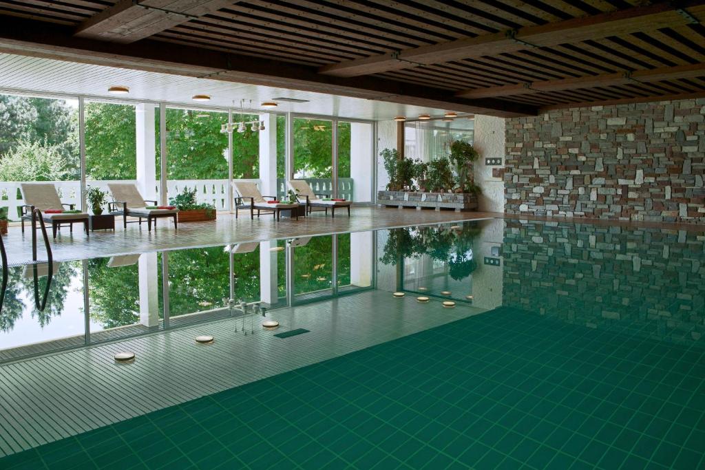 a swimming pool with a green floor and windows at Hotel Mayer in Germering