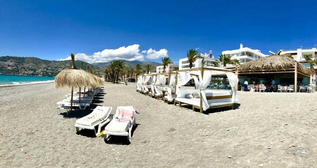 a group of lounge chairs and umbrellas on a beach at villaquinta in La Herradura