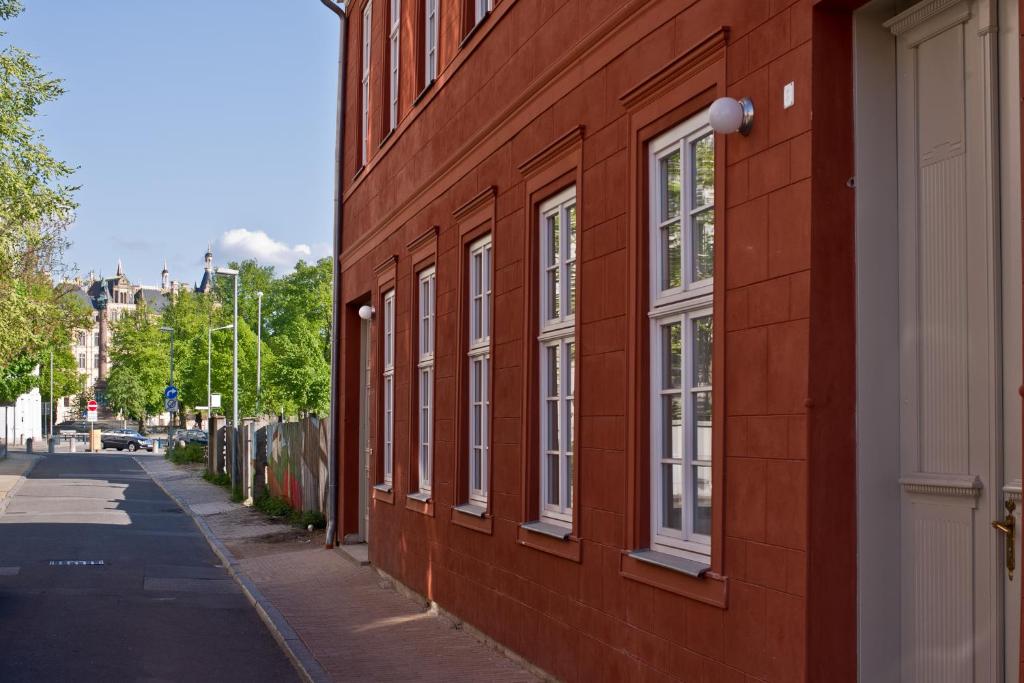 um edifício de tijolos vermelhos com janelas brancas numa rua em Ferienwohnung Klosterstraße direkt am Schloß em Schwerin