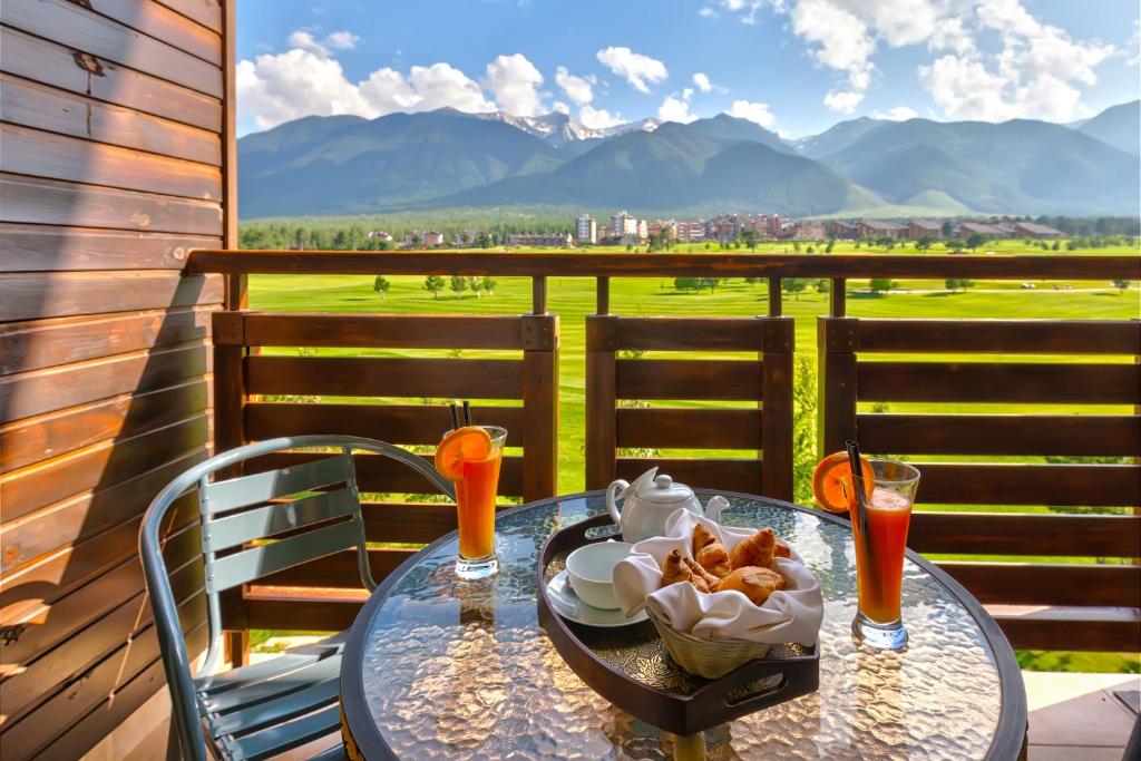 ein Tisch mit einer Schüssel Essen und Getränken auf einem Balkon in der Unterkunft Terra Hotel in Bansko